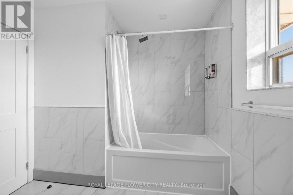 White bathtub with marble tile shower and dispenser - 79 Kimberly Drive Hamilton