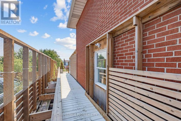 Wooden walkway and red brick building with privacy screens - 79 Kimberly Drive Hamilton