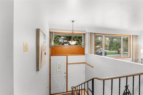 Interior foyer with a white front door, wood trim, and large windows overlooking the street. - 79 Mattinee Bay, Winnipeg