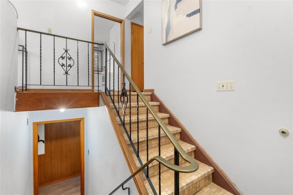 Interior view looking down a staircase with a metal railing and wood accents. - 79 Mattinee Bay, Winnipeg