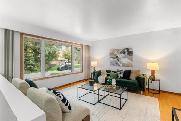 Living room with a large window, green sofa, glass coffee table, and neutral rug. - 79 Mattinee Bay, Winnipeg