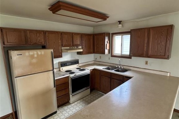 Kitchen with dark wood cabinets, beige countertops, and a window above the sink. - 79 Parkside, Mcgregor