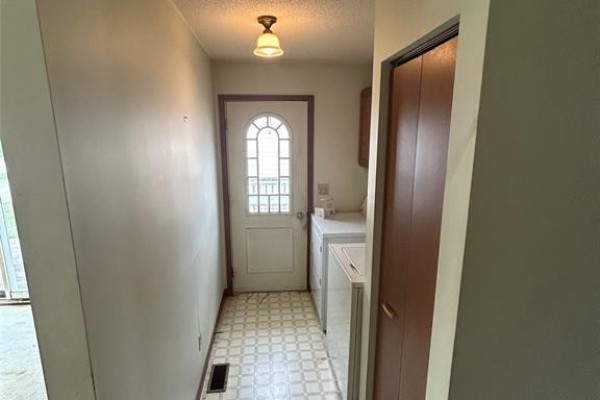 Hallway with linoleum flooring, a front door, and a washer and dryer. - 79 Parkside, Mcgregor
