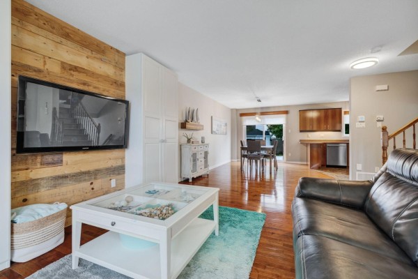 Open-concept living and dining area with hardwood floors, a television, and kitchen in the background. - 79 Rue Du Frimas, Gatineau