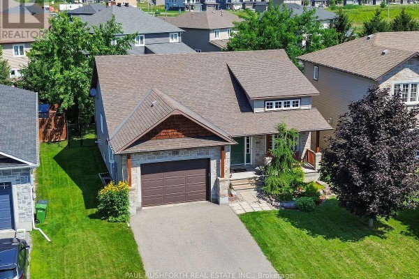 Aerial view of the front exterior of a stone and wood-sided house with a brown garage door and green front door. - 79 Settlement Lane, Russell
