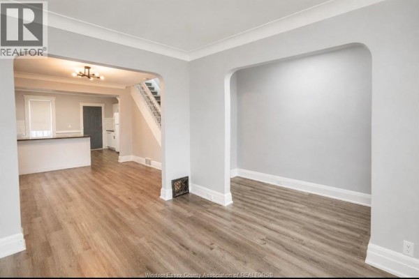 Living room with gray walls, wood-look flooring, and archways to dining and kitchen areas. - 790 Marentette, Windsor