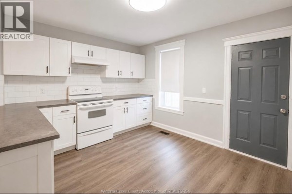 White kitchen with gray countertops, white appliances, subway tile backsplash, and gray door. - 790 Marentette, Windsor