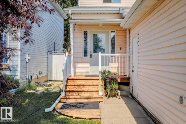 Wooden steps lead up to the front entrance of a house with a glass-paned door. - 7912 154 Av Nw, Edmonton