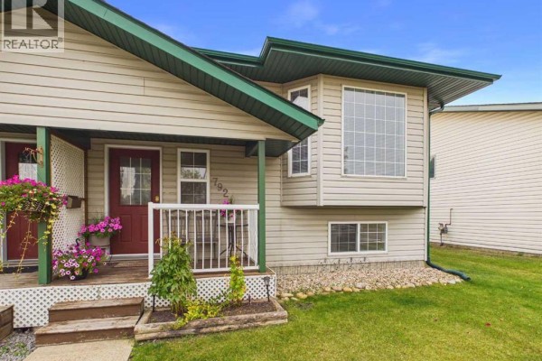 Front view of a beige duplex with a bay window on the right side and a covered porch on the left. - 792 Lancaster Drive, Red Deer