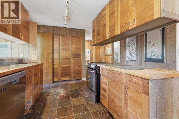 Kitchen with wood cabinetry, tile countertops, a stainless steel refrigerator, and views of the garden. - 792 W 54th Avenue, Vancouver