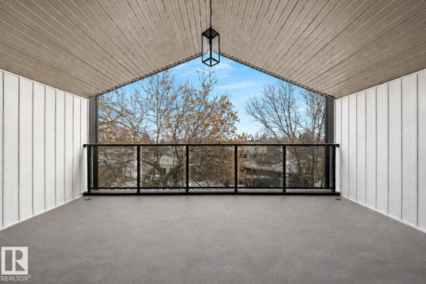 Covered balcony with a view of trees and houses through a glass railing. - 7927 112s Av Nw, Edmonton