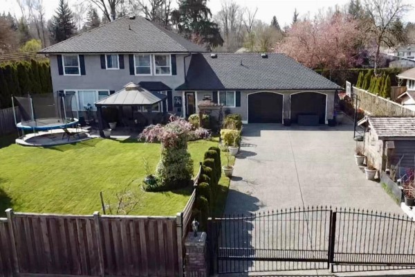 View of a long driveway leading to a gated entrance of a residential property. - 7930 144 Street, Surrey