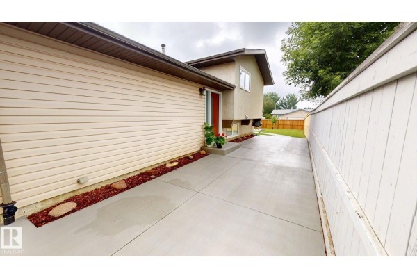 Side view of the house with a long concrete driveway leading to a detached garage. - 7935 22 Av Nw, Edmonton