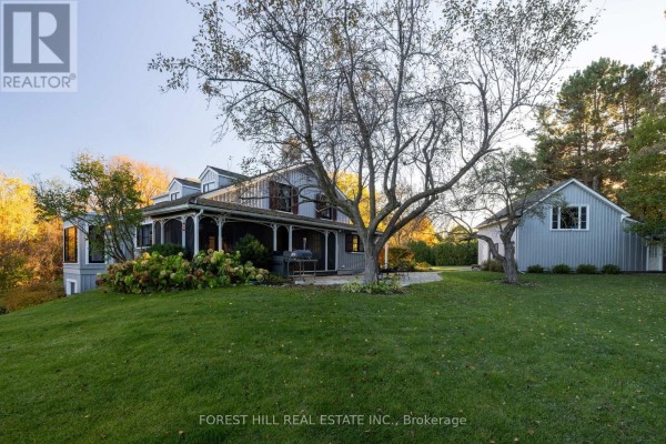 Side view of a grey house with a wraparound porch and a detached garage. - 794575 Mono Centre Road, Mono