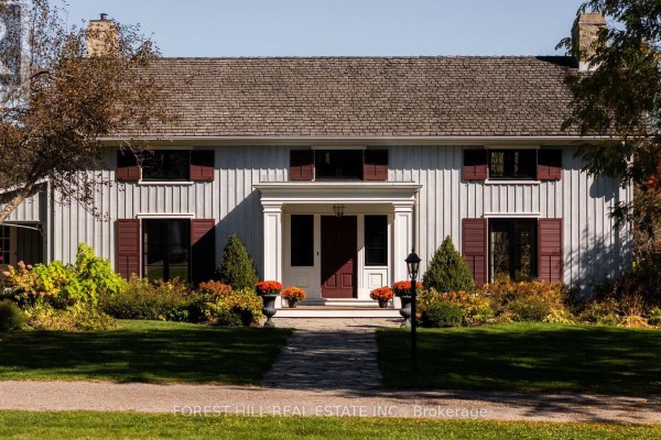 Front facade of a light grey clapboard house with dark shutters and a central entrance. - 794575 Mono Centre Road, Mono