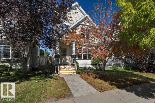 Front exterior of a yellow house with a covered porch and stairs. - 7948 13 Av Sw, Edmonton