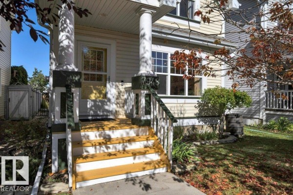 Spacious living area with hardwood floors, fireplace, and view of kitchen stairs. - 7948 13 Av Sw, Edmonton