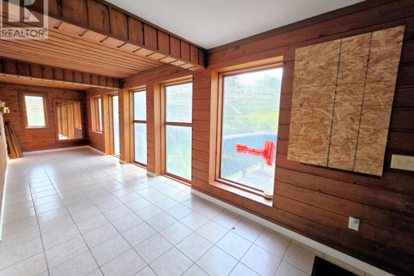 Interior sunroom with tiled floors, wood-paneled walls, and large windows overlooking a pool area. - 795 Dominion Street, Mcbride   Town