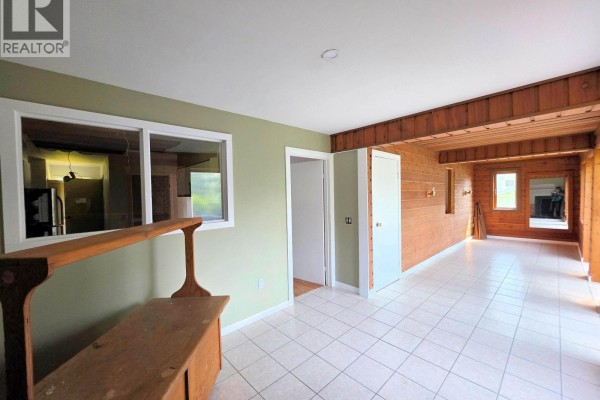 Interior view of a room with tiled floors, light green walls, and wood-paneled accent walls. - 795 Dominion Street, Mcbride   Town