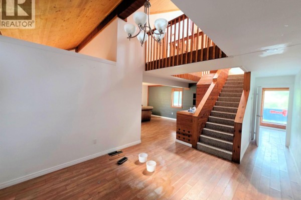Living room with vaulted wood ceilings, a staircase, and light wood laminate flooring. - 795 Dominion Street, Mcbride   Town