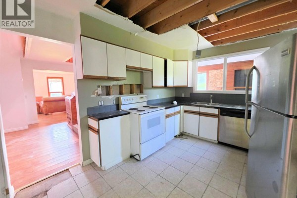 Kitchen with white cabinets, white appliances, stainless steel refrigerator, and tiled floors. - 795 Dominion Street, Mcbride   Town