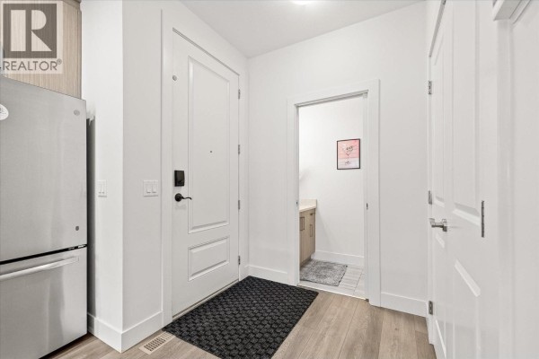 Bright interior entryway with a stainless steel refrigerator, white doors, and a black doormat. - 795 Stockwell Avenue Unit# 3, Kelowna