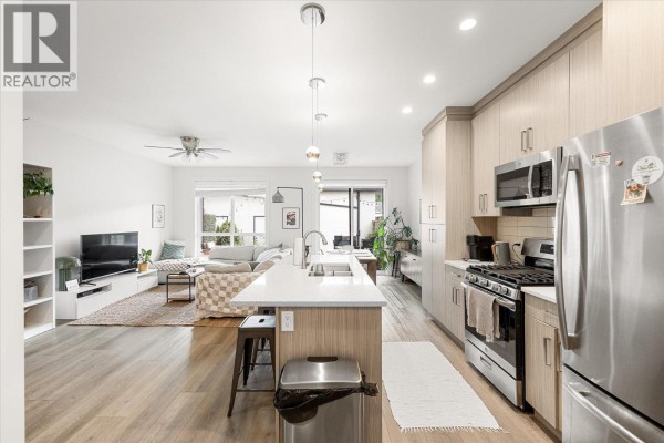 Open concept living and kitchen area with light wood cabinets, white countertops, and a large island. - 795 Stockwell Avenue Unit# 3, Kelowna