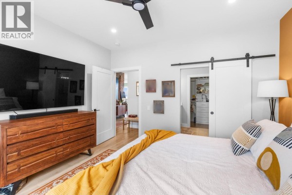 Bedroom with large TV, dresser, bed, and barn door leading to closet. - 796 Kuipers Crescent Unit# 2, Kelowna