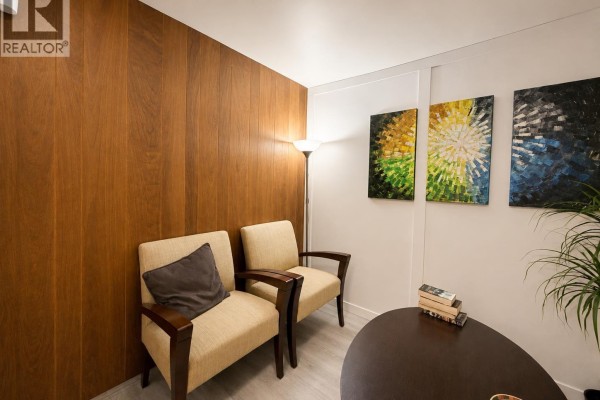 Sitting area with two upholstered chairs, wood paneling, and abstract art on the wall. - 796 W 42nd Avenue, Vancouver
