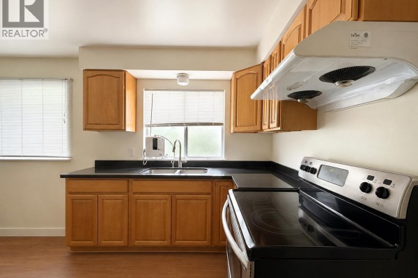 Kitchen with light wood cabinets, black countertops, stainless steel appliances, and a window. - 796 W 42nd Avenue, Vancouver