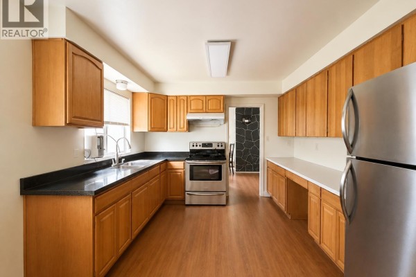 Spacious kitchen with ample light wood cabinetry, black countertops, and stainless steel refrigerator. - 796 W 42nd Avenue, Vancouver