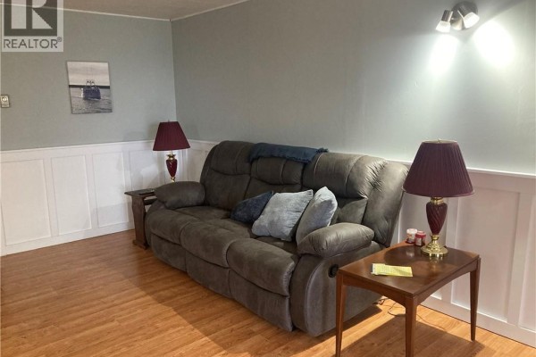 Bedroom with grey plaid comforter, two windows with grey curtains, and mounted television. - 798 North Road, Welshpool