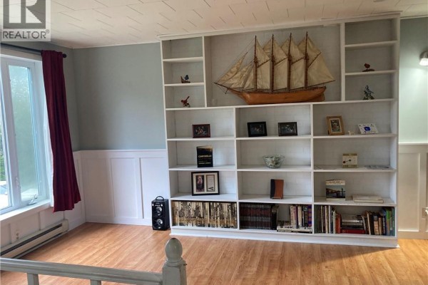 Living room with floral patterned sofa, armchair, large trunk, and wooden shelving unit. - 798 North Road, Welshpool