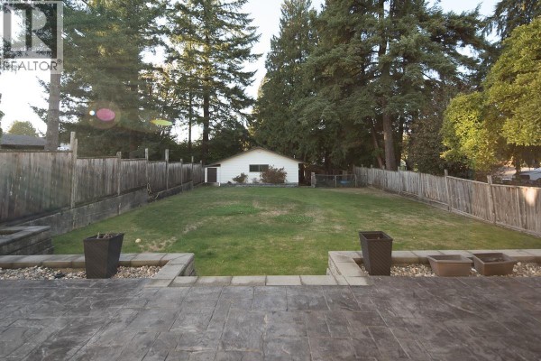 Detached garage with white siding, a large roll-up door, and a side door. - 7981 Rosewood Street, Burnaby