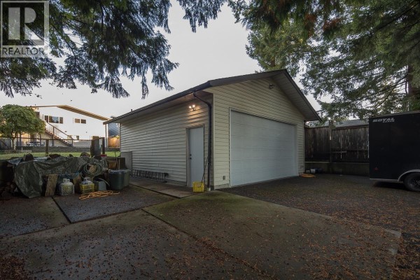 White kitchen with gray granite countertops, stainless steel appliances, and a view of the hallway. - 7981 Rosewood Street, Burnaby