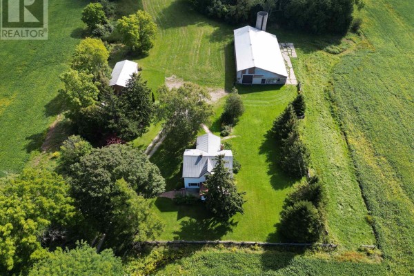 Expansive aerial panorama showcasing farmland, wooded areas, a farmhouse, and distant industrial structures. - 79888 Bluewater Highway, Central Huron