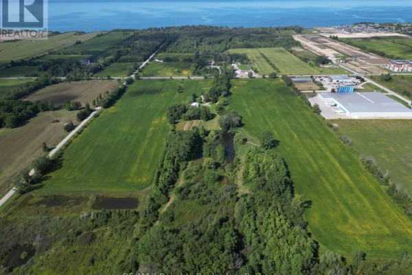 Close-up aerial view of a white farmhouse with a metal roof, porch, and surrounding green lawn. - 79888 Bluewater Highway, Central Huron