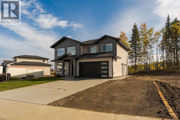 Front view of a modern grey and white two-story house with a driveway and surrounding construction. - 7990 Southridge Avenue, Prince George