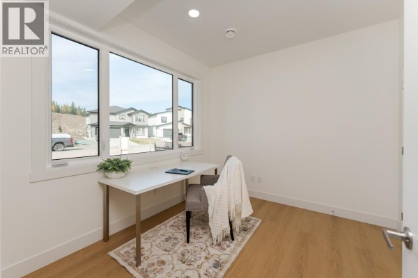 Small room with a desk, chair, and large window overlooking houses and a street. - 7990 Southridge Avenue, Prince George