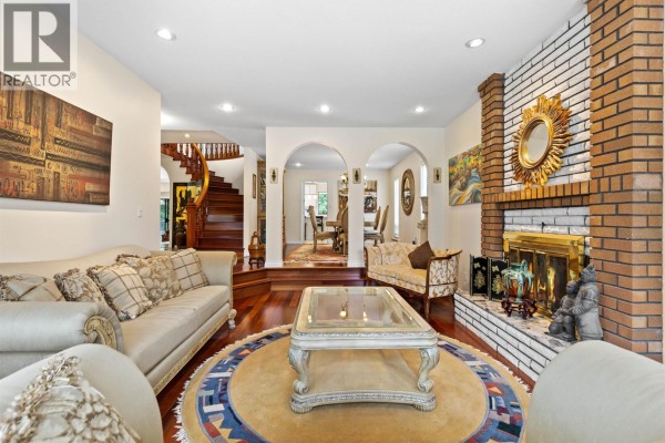 Living room fireplace, arched doorways to dining and hallway, and wood floors. - 7995 Woodhurst Drive, Burnaby