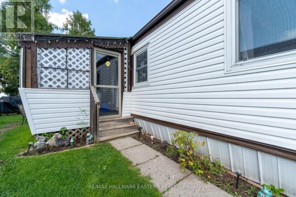 Close-up of the mobile home's entrance with wooden steps and a screened door. - 7a - 2244 Heritage Line, Otonabee South Monaghan