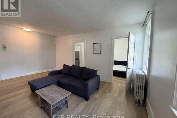Living room with a blue sectional sofa and grey coffee table. Two doorways are visible. - 8 - 102 Greensides Avenue, Toronto