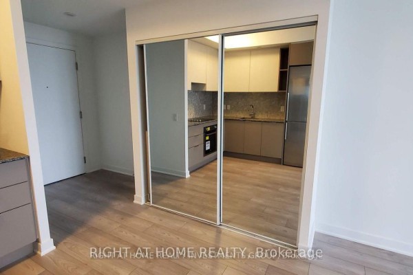 View of a kitchen through mirrored closet doors in a condo unit. - 1408 - 120 Parliament Street, Toronto