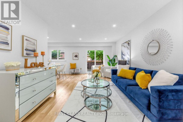 Living room with a blue sectional sofa, white armchairs, and light wood floors. - 8 - 16 Woodglen Way, Markham