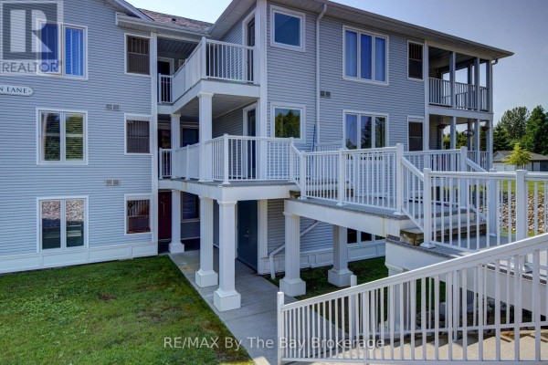 Close-up exterior view of apartment building entrance with white railings and stairs. - 8 - 30 Mulligan Lane, Wasaga Beach