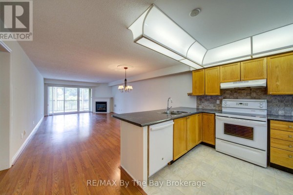 Open concept kitchen and living area with wood floors, fireplace, and wood cabinetry. - 8 - 30 Mulligan Lane, Wasaga Beach
