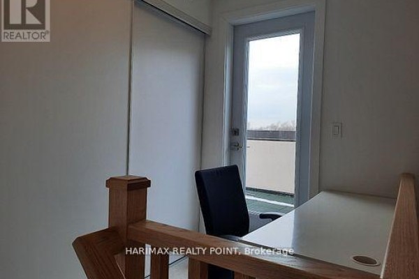 Small workspace with a white desk, black chair, and glass door leading to a balcony. - 8 - 4015 Hickory Drive, Mississauga