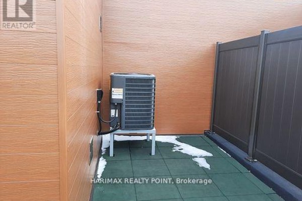 Outdoor air conditioning unit on a green mat surface with wood siding and dark fence. - 8 - 4015 Hickory Drive, Mississauga
