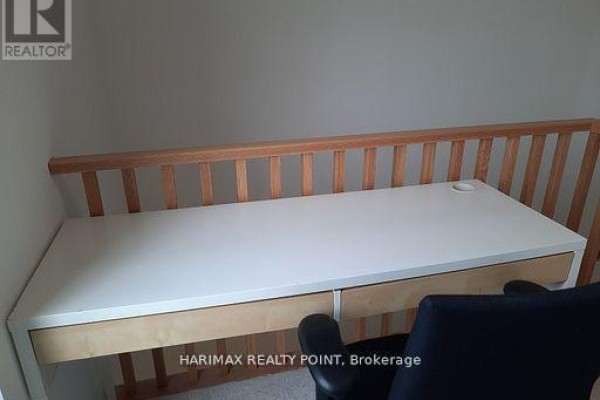 White desk with drawers and a black chair against a light grey wall with wooden railing. - 8 - 4015 Hickory Drive, Mississauga