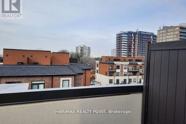 View of multi-story buildings from a balcony with beige concrete railing and dark fence. - 8 - 4015 Hickory Drive, Mississauga